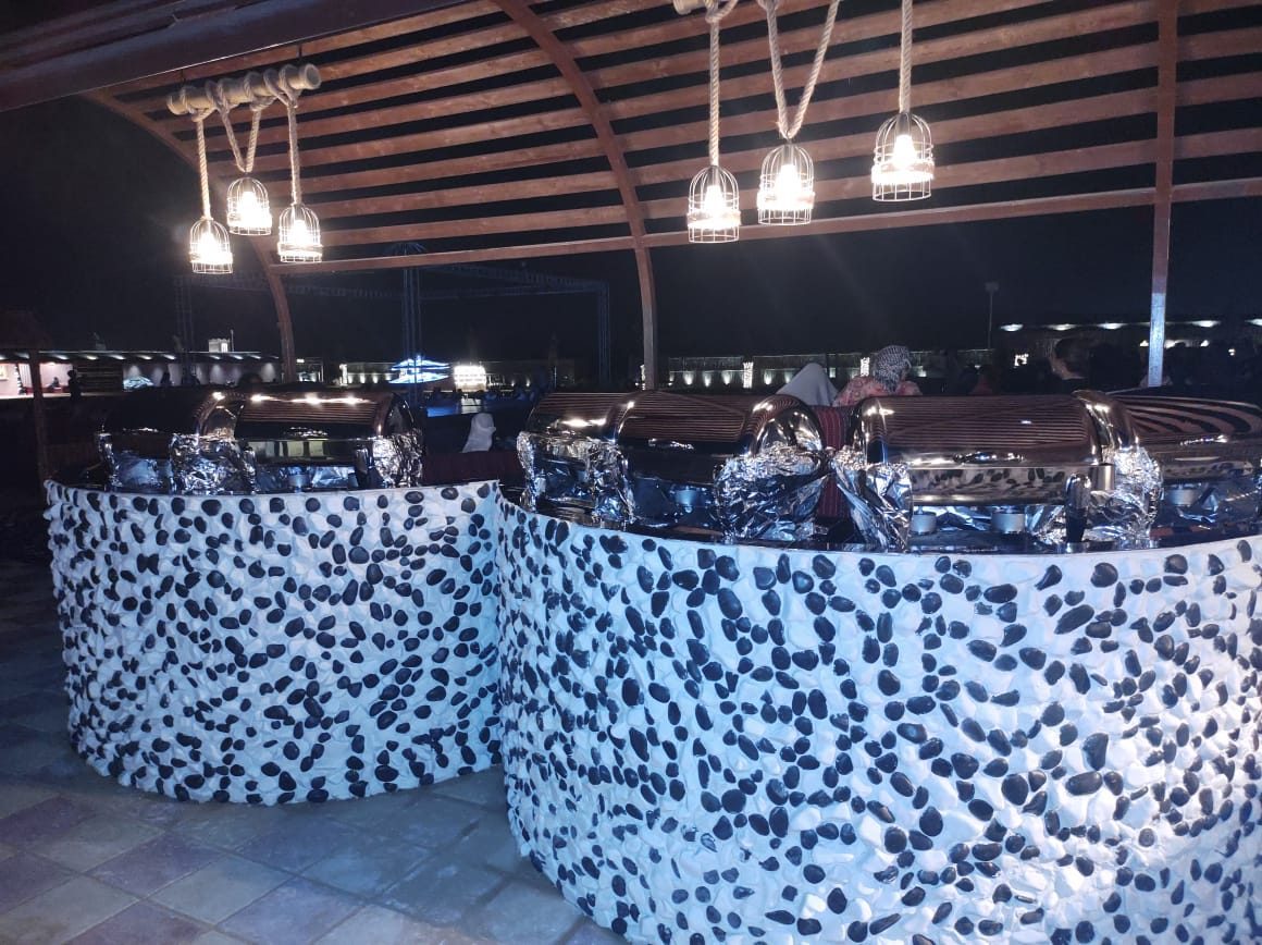 Buffet counters prepared under the shelter at a desert safari camp