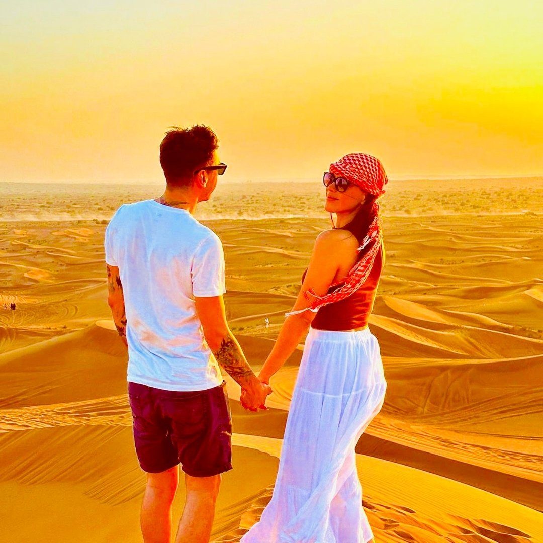 Couple enjoying the sunset over golden desert dunes