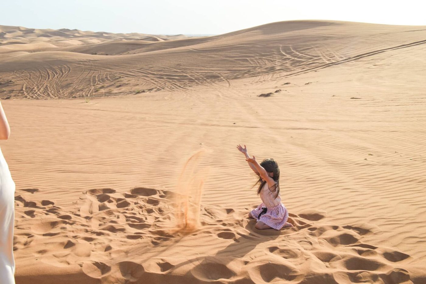 Visitor sliding down a dune on a sandboard