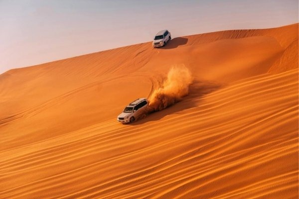 Four-wheel-drive vehicles dune bashing on a steep Dubai sand dune