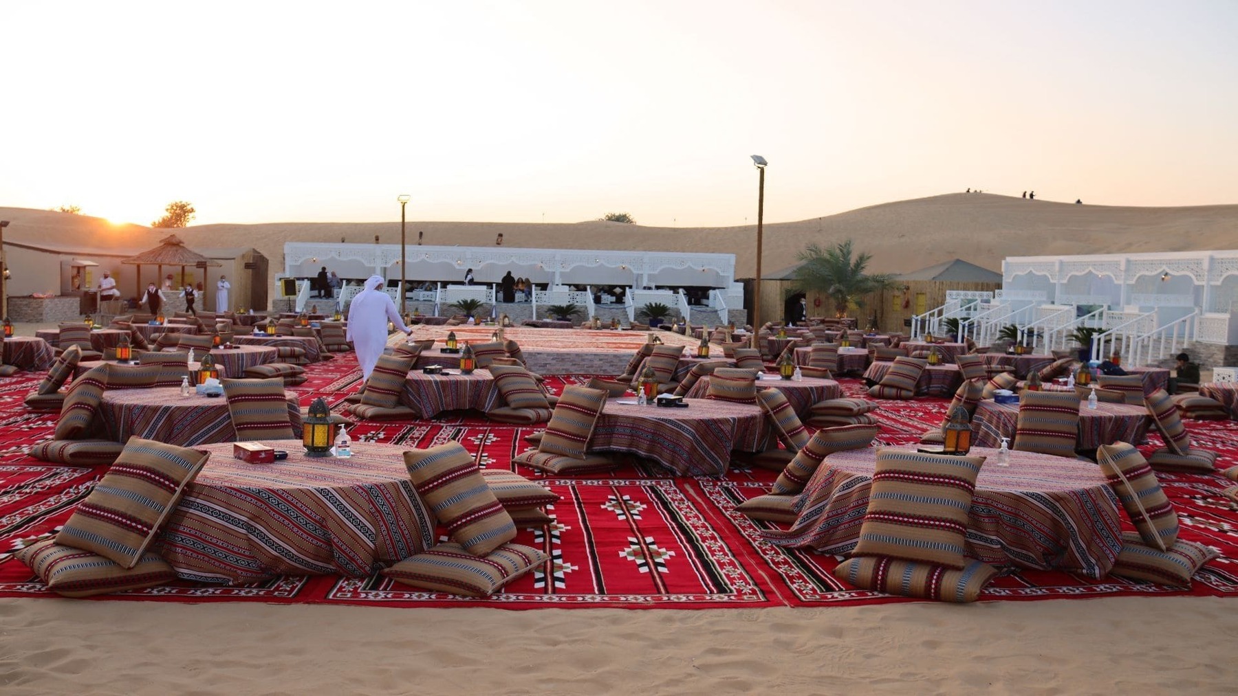 Low tables and cushioned seats prepared for dinner at a Dubai desert camp