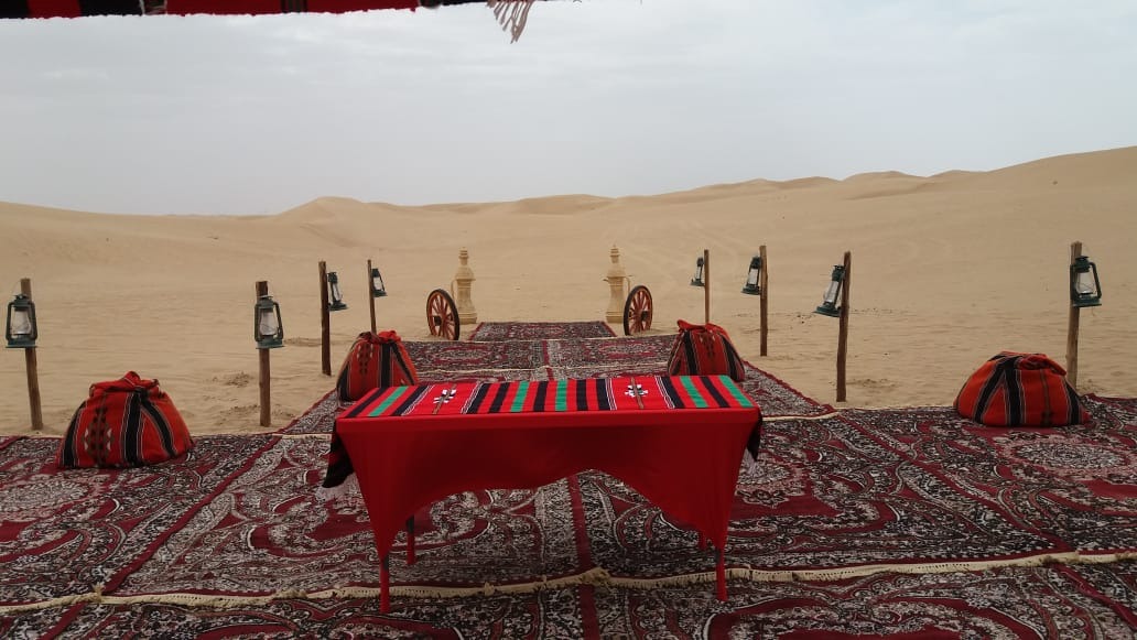 Sheltered outdoor majlis dining table overlooking Dubai desert dunes